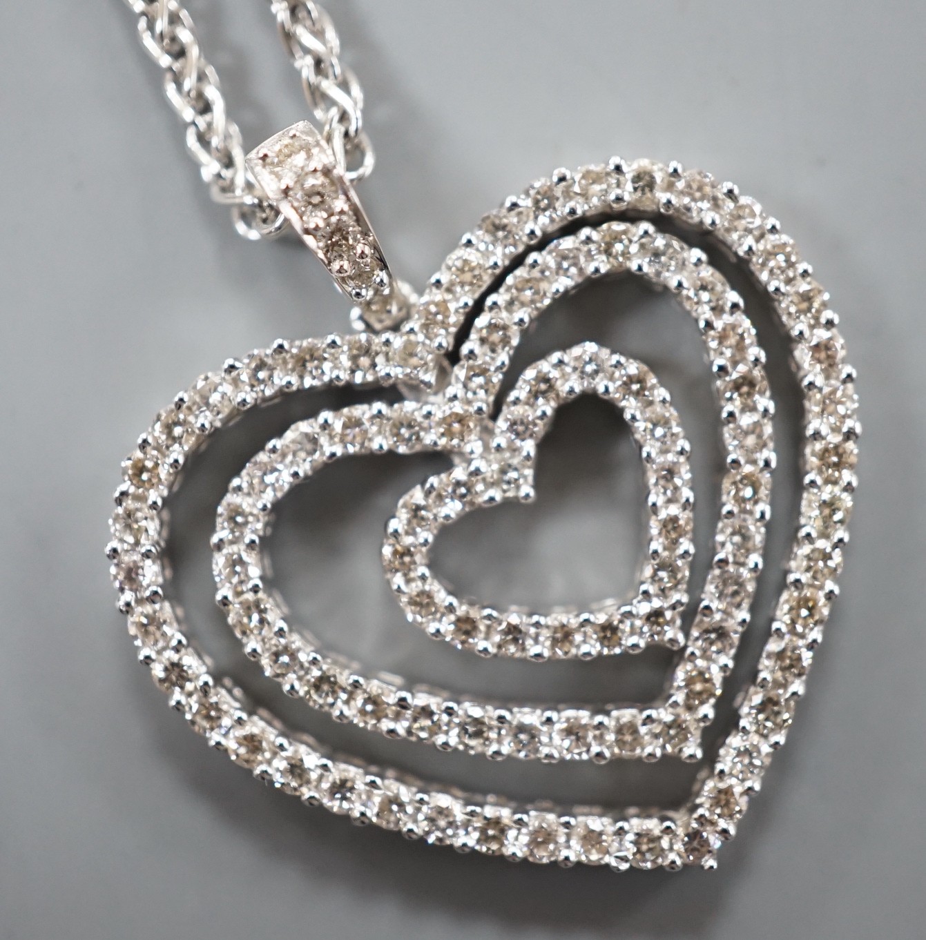 A modern 18k white metal and diamond set graduated concentric heart pendant, 27mm, on an 18ct white gold chain, 44cm, gross weight 11.3 grams